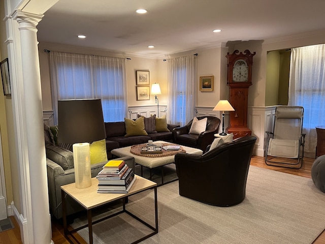 living room featuring crown molding, decorative columns, and light hardwood / wood-style flooring