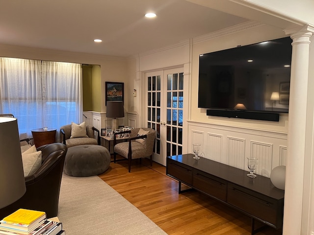 living room with crown molding, light hardwood / wood-style flooring, french doors, and ornate columns