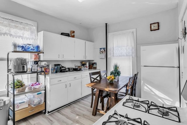 kitchen with white appliances, white cabinetry, and plenty of natural light