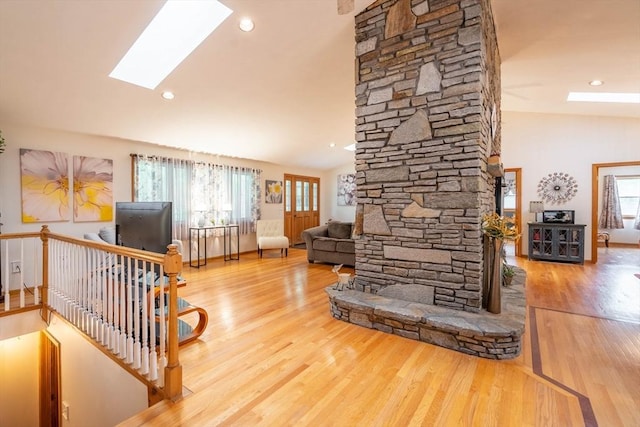 living room with a skylight, healthy amount of natural light, wood finished floors, vaulted ceiling, and recessed lighting