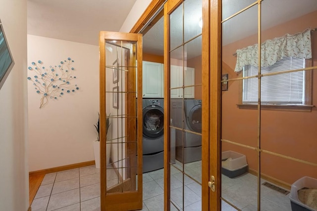 doorway with french doors, washing machine and clothes dryer, light tile patterned flooring, and baseboards
