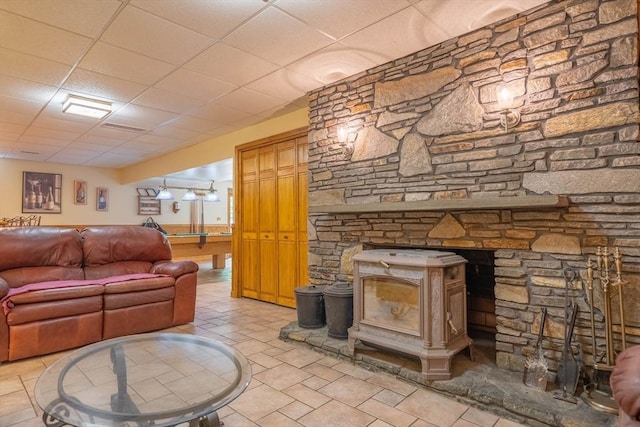 living room with a paneled ceiling and a wood stove