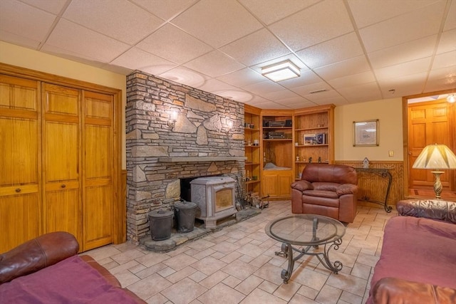 living area with a wood stove, built in shelves, and a paneled ceiling