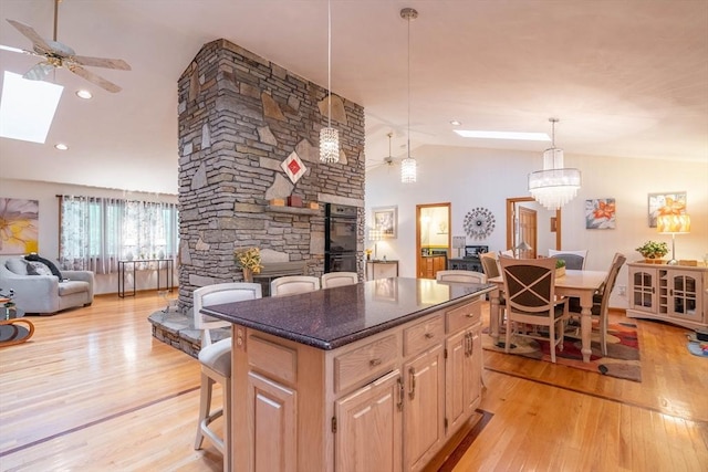 kitchen featuring light wood-style floors, a kitchen island, a kitchen bar, a ceiling fan, and open floor plan