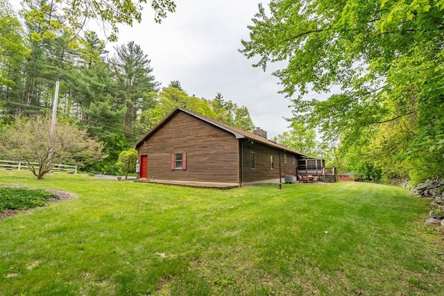 view of side of home with a chimney and a yard