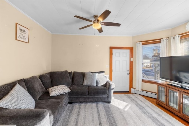 living area with a ceiling fan, crown molding, a baseboard heating unit, and wood finished floors