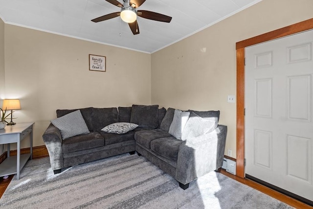 living area with a ceiling fan, crown molding, baseboards, and wood finished floors