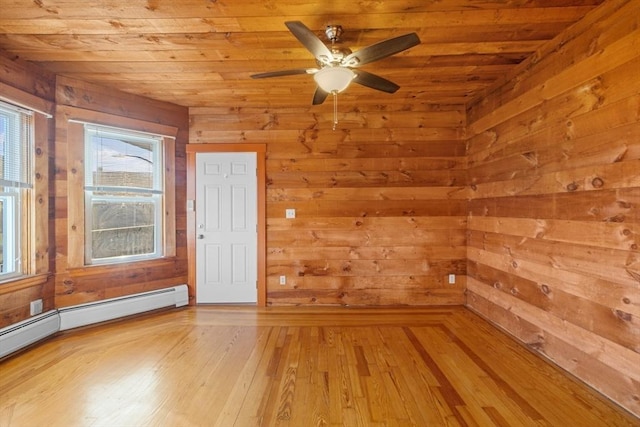 empty room with wooden walls, a baseboard radiator, wood ceiling, and light wood-style floors