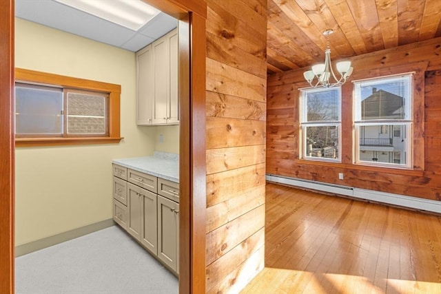 kitchen featuring a baseboard radiator, gray cabinets, light countertops, and wooden walls