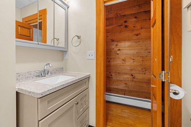 bathroom with a baseboard radiator, wood finished floors, and vanity