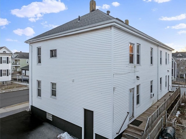 view of property exterior featuring roof with shingles and a chimney