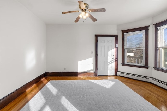 unfurnished room with ceiling fan, baseboards, baseboard heating, and wood finished floors