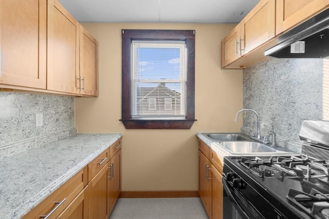 kitchen with tasteful backsplash, baseboards, range with gas cooktop, under cabinet range hood, and a sink