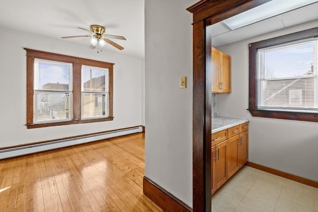 kitchen featuring ceiling fan, a baseboard heating unit, baseboards, light countertops, and light wood-type flooring