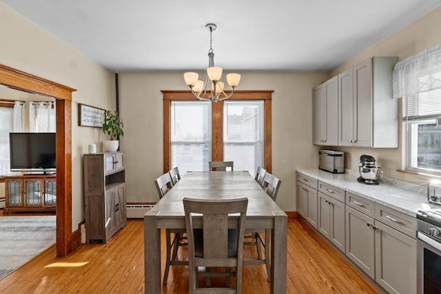 dining room featuring a baseboard radiator, baseboards, a notable chandelier, and light wood finished floors