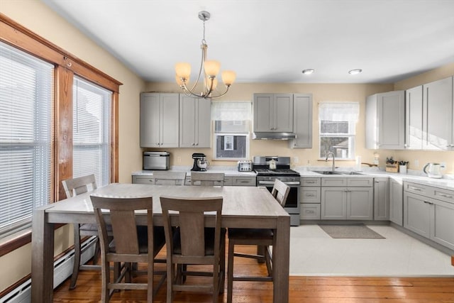 kitchen with stainless steel gas stove, gray cabinets, a sink, and light countertops