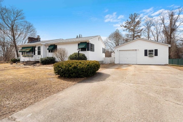 view of front facade with an outdoor structure, concrete driveway, fence, and a chimney