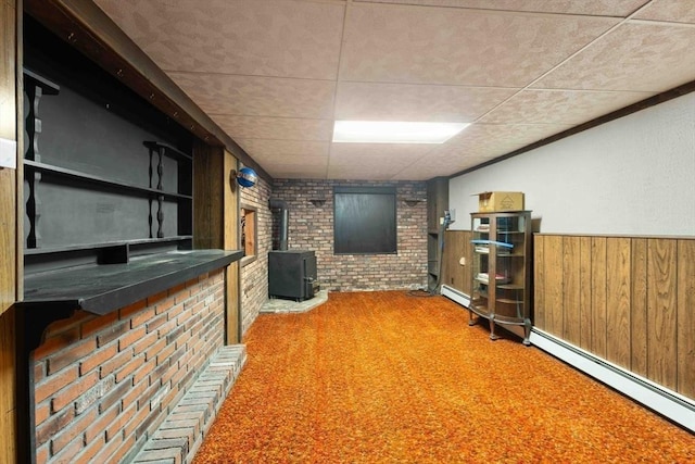 bar with brick wall, carpet, a wainscoted wall, a wood stove, and a baseboard radiator