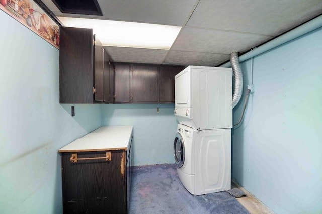 clothes washing area with cabinet space and stacked washer / drying machine