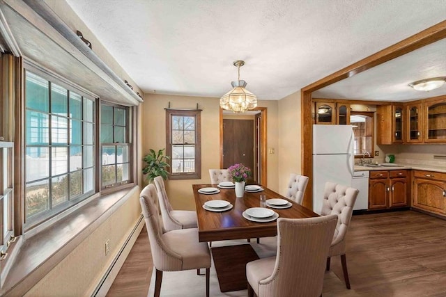 dining space with a notable chandelier, dark wood-type flooring, baseboard heating, and a textured ceiling