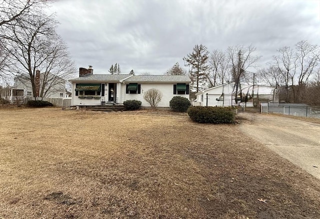 ranch-style home with a front lawn, a chimney, and fence