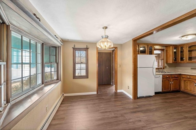 kitchen with brown cabinets, dark wood-style floors, white appliances, light countertops, and glass insert cabinets