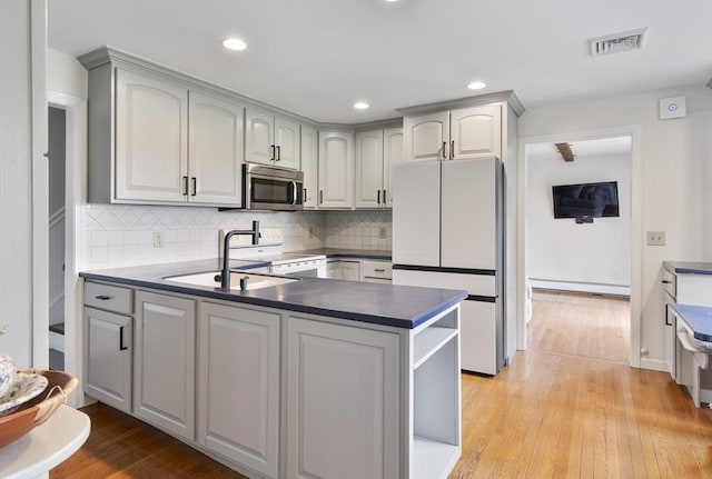 27 N Brigham Hill Rd, Grafton, MA 01536 - kitchen with white appliances, a peninsula, light wood-type flooring, backsplash, and dark countertops