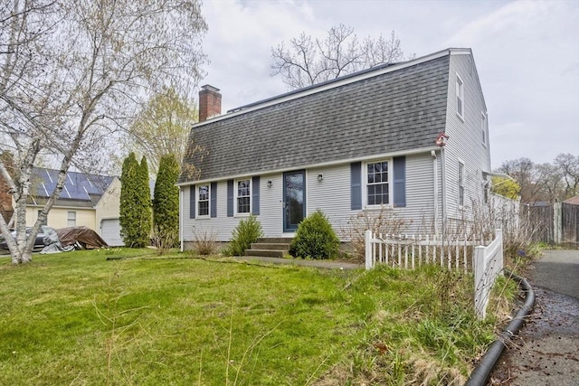 colonial inspired home featuring a chimney, a front yard, fence, a gambrel roof, and a shingled roof