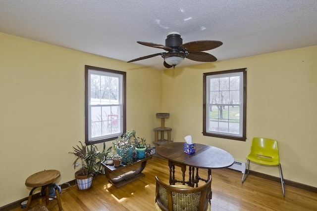 dining area with baseboard heating, baseboards, a ceiling fan, and wood finished floors
