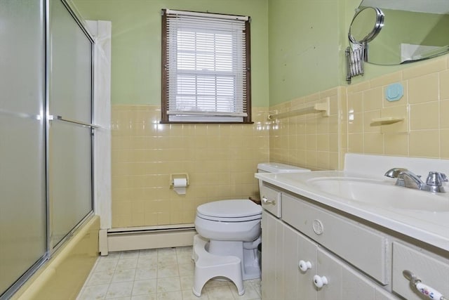 full bath with wainscoting, baseboard heating, vanity, toilet, and tile walls