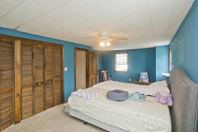 carpeted bedroom with ceiling fan and a closet