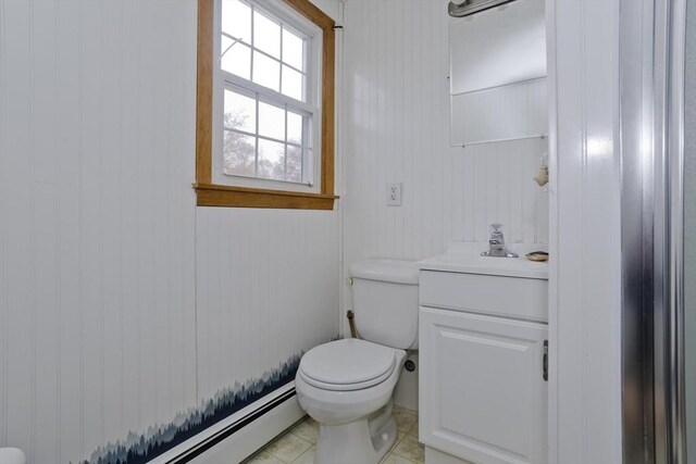 half bath with vanity, tile patterned flooring, a baseboard heating unit, and toilet