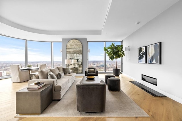 living room with a wall of windows, a wealth of natural light, and light hardwood / wood-style flooring