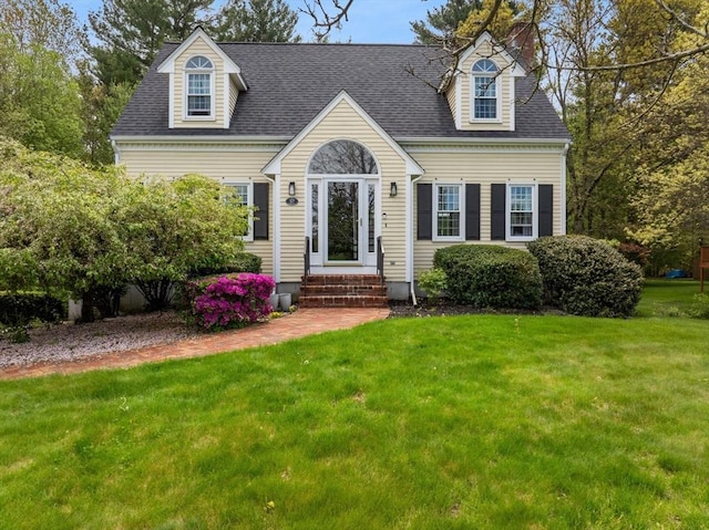 new england style home featuring a front yard and a shingled roof