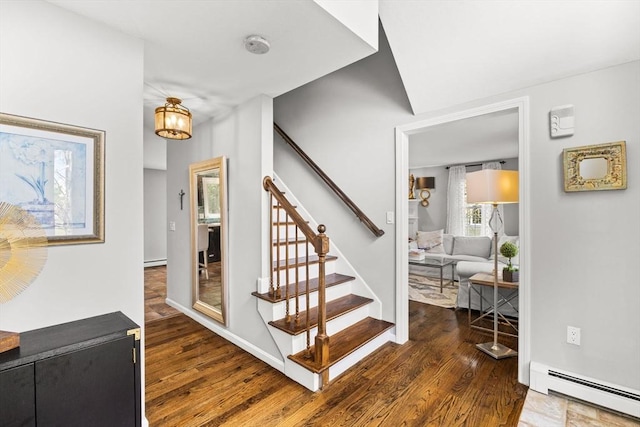 staircase featuring a baseboard heating unit and wood finished floors