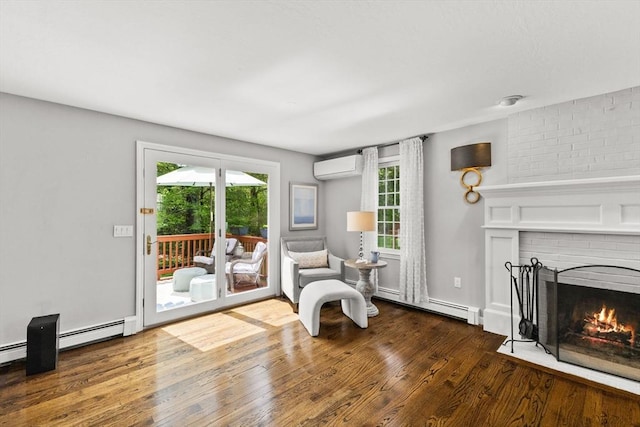 sitting room featuring baseboard heating, wood finished floors, a brick fireplace, and a wall unit AC