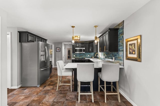 kitchen with appliances with stainless steel finishes, a peninsula, a sink, baseboards, and decorative backsplash