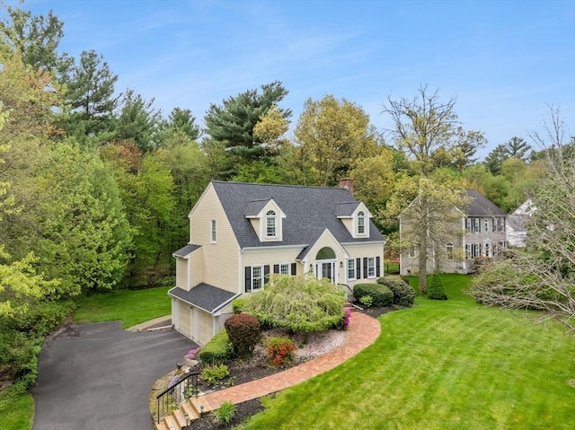 view of front of home featuring a garage, a chimney, driveway, a front yard, and a shingled roof