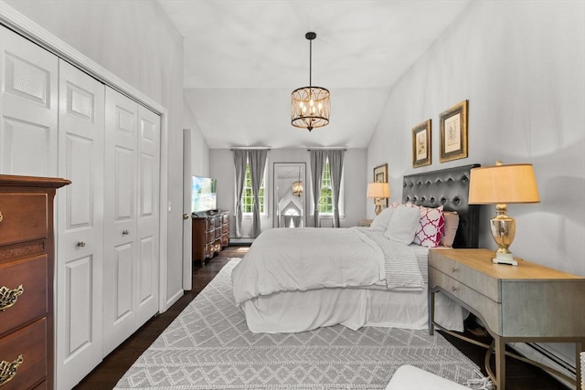bedroom featuring vaulted ceiling, a chandelier, a closet, and dark wood-style floors