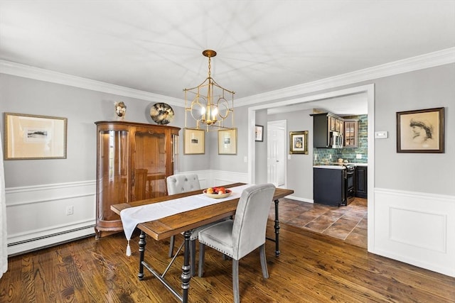 dining room featuring a baseboard heating unit, ornamental molding, a wainscoted wall, a chandelier, and dark wood finished floors