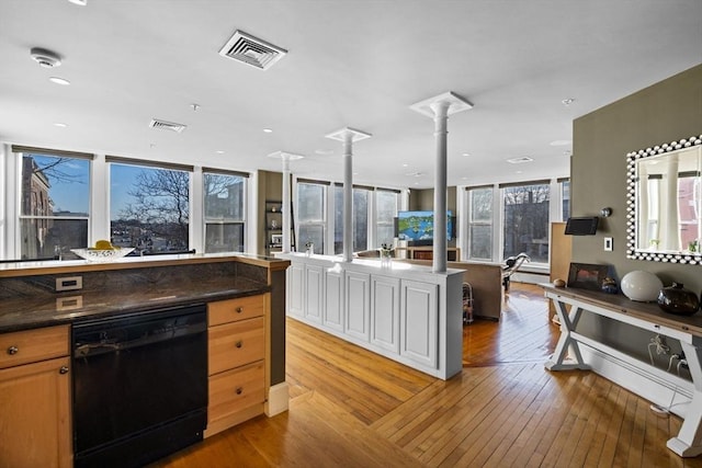 kitchen featuring decorative columns, dishwasher, a kitchen island, and light hardwood / wood-style floors