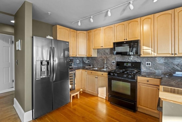 kitchen with light brown cabinetry, backsplash, light hardwood / wood-style floors, and black appliances