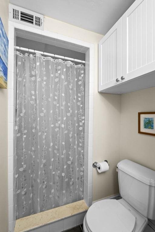 bathroom featuring toilet and curtained shower