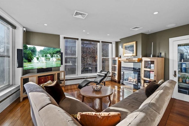 living room featuring hardwood / wood-style floors, plenty of natural light, and a tiled fireplace