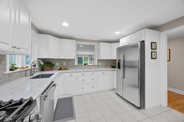 2 Darby Pt Unit 2, Mashpee, MA 02649 - kitchen with appliances with stainless steel finishes, tasteful backsplash, white cabinets, light tile patterned flooring, and light stone countertops