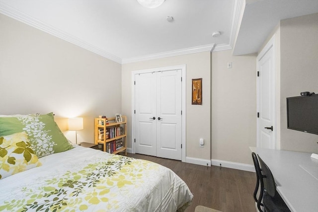 bedroom with dark wood-style flooring, ornamental molding, baseboards, and a closet