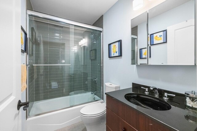 bathroom featuring toilet, vanity, and shower / bath combination with glass door