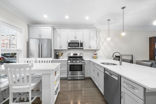 kitchen featuring appliances with stainless steel finishes, a sink, a peninsula, tasteful backsplash, and light countertops