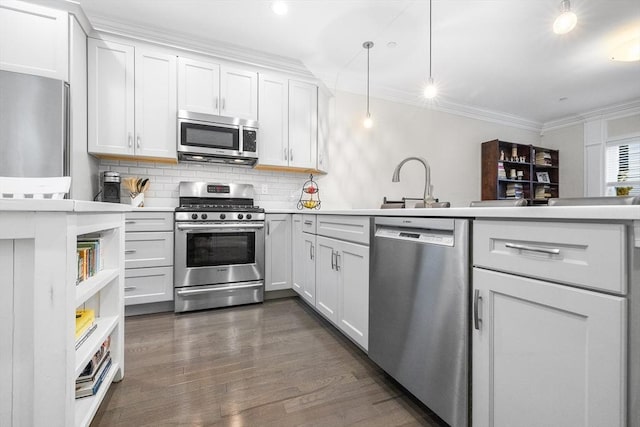 kitchen featuring appliances with stainless steel finishes, a peninsula, light countertops, tasteful backsplash, and ornamental molding