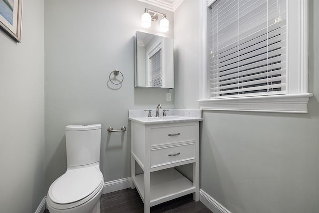 bathroom featuring baseboards, ornamental molding, toilet, wood finished floors, and vanity